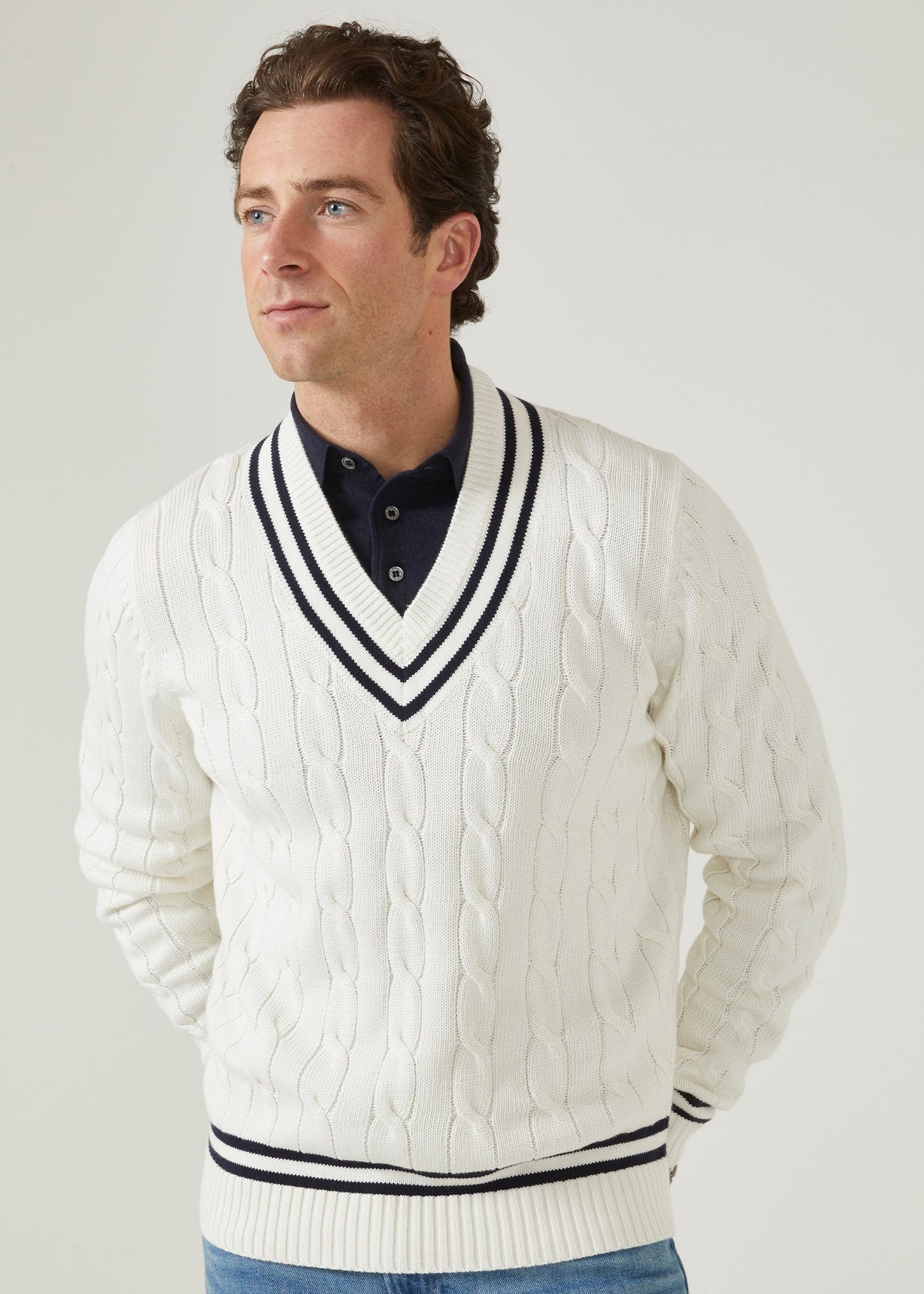 Men's ecru vee neck cable knit cricket jumper with dark navy trim.